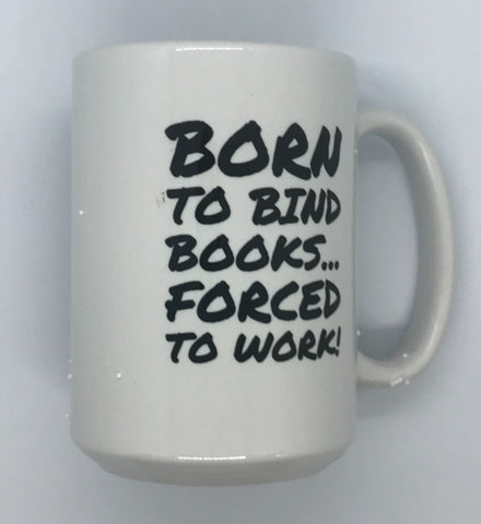 White mug with black lettering that reads "Born to bind books...forced to work!".