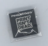 White pin with the words "Print isn't dead." in black letters.